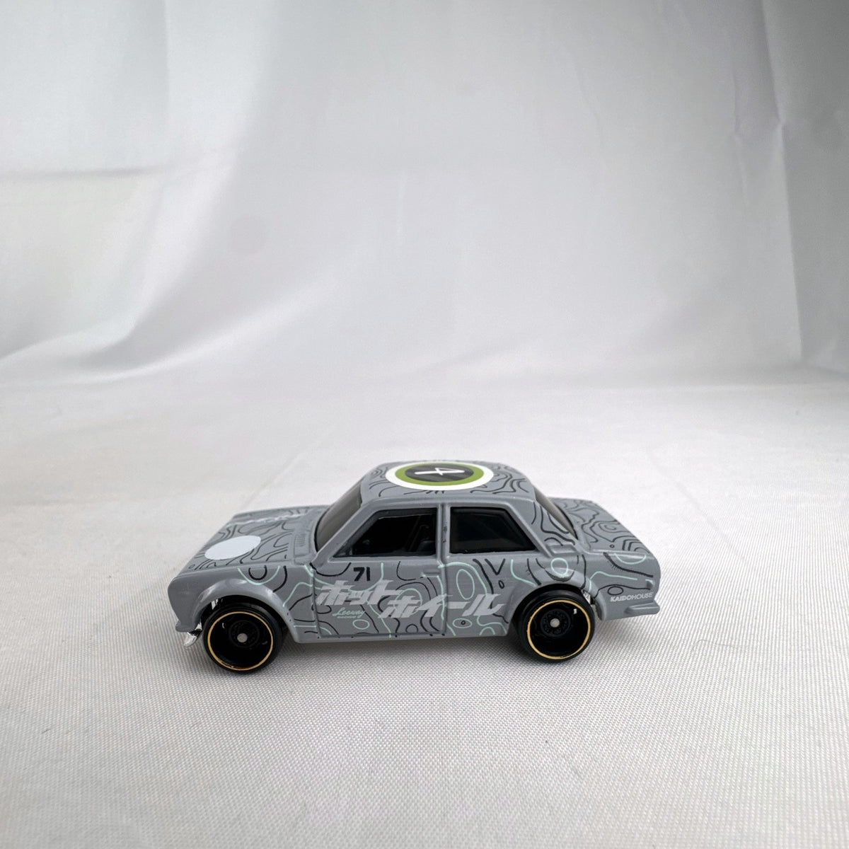 Hot Wheels 1:64 scale 1971 Datsun Bluebird 510 diecast car in grey with Kaido House topographic graphics