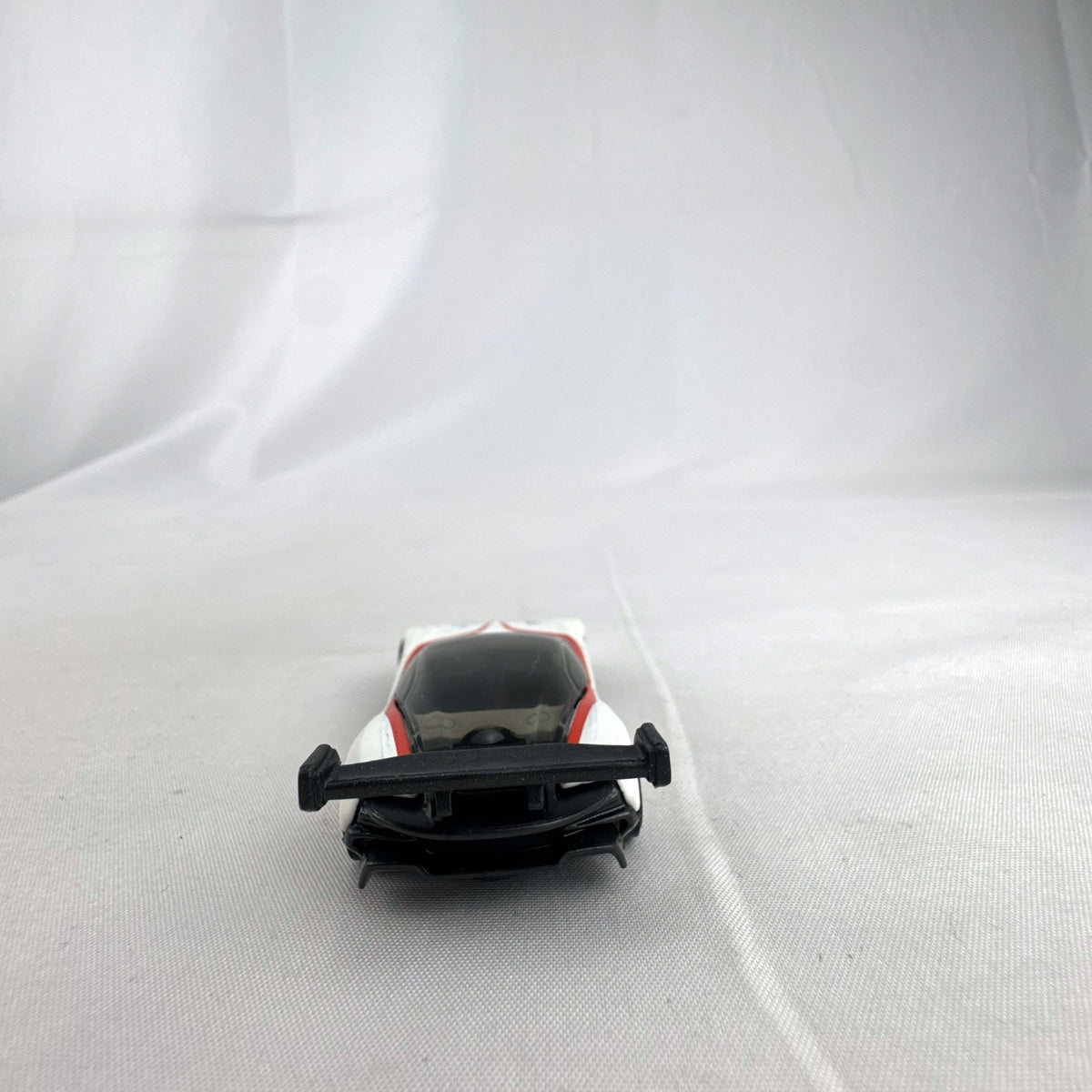 White Hot Wheels 1:64 scale Aston Martin Vulcan diecast car with red racing stripes and black rear wing