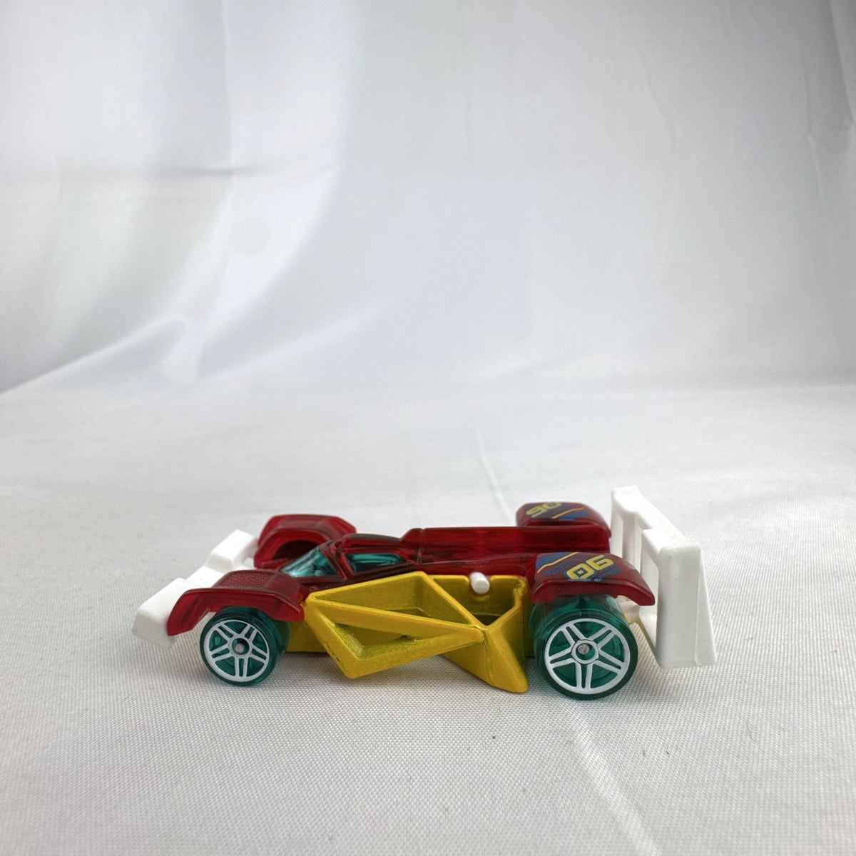Hot Wheels Track Hammer X-Raycers diecast race car in translucent red with yellow chassis and teal wheels