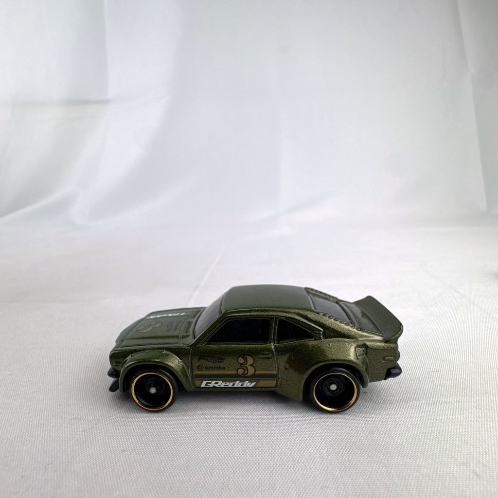 Hot Wheels 1:64 scale Mazda RX-3 diecast car in dark metallic green with GReddy racing livery