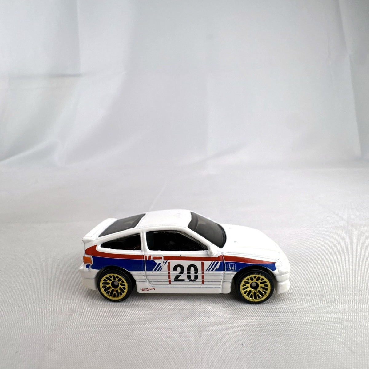 Hot Wheels 1988 Honda CRX diecast car in white HW Speed Graphics racing livery with gold wheels.