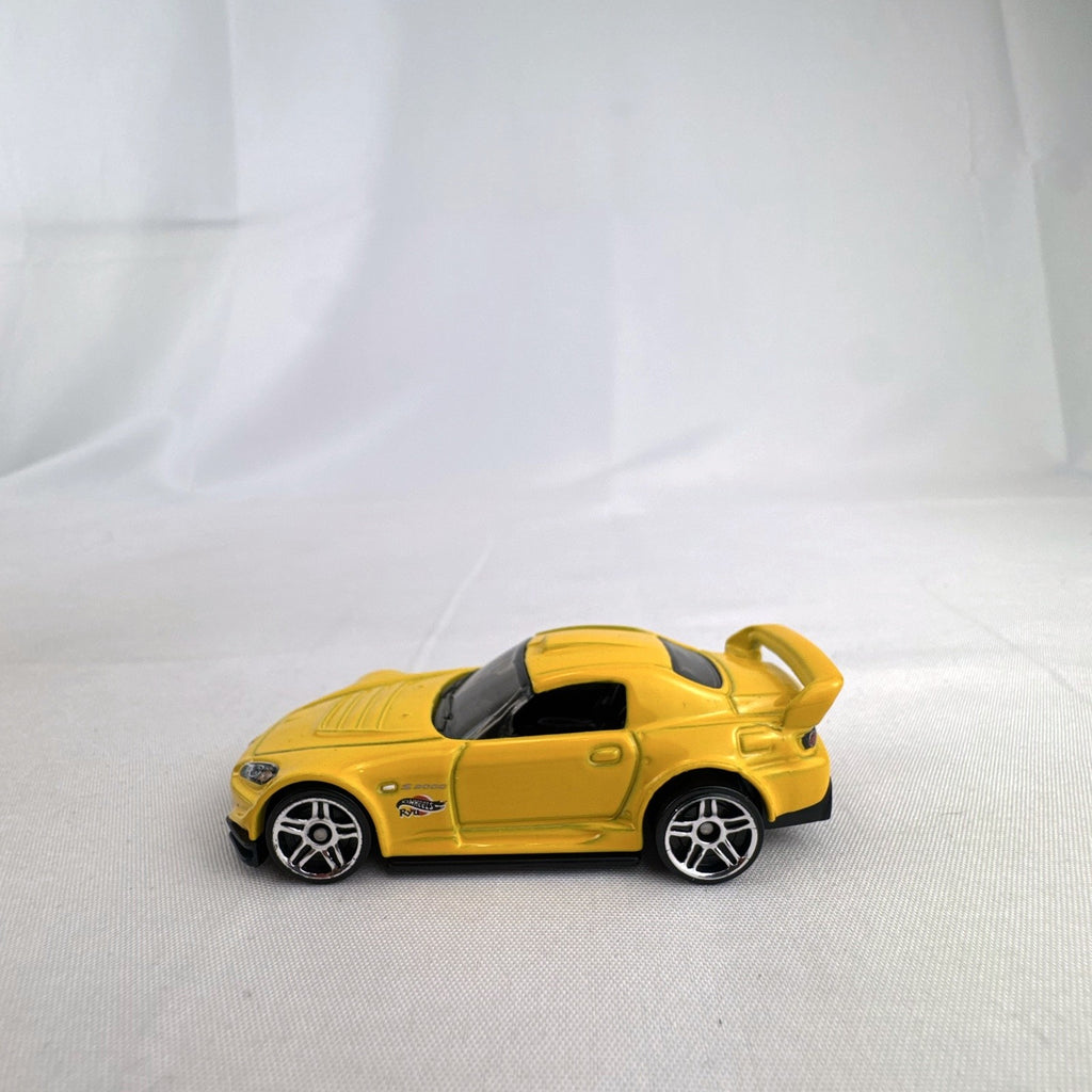 Yellow 1:64 scale Hot Wheels Honda S2000 diecast car featuring Ryu Asada tribute graphics