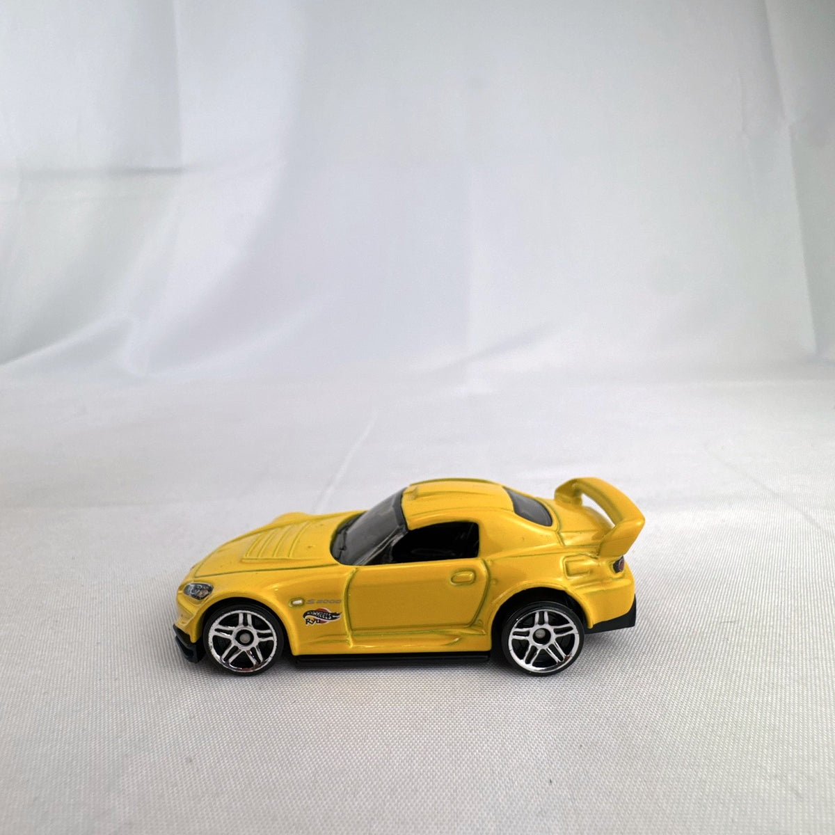 Yellow 1:64 scale Hot Wheels Honda S2000 diecast car featuring Ryu Asada tribute graphics