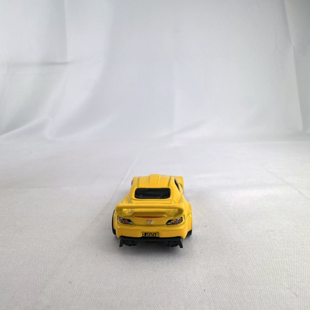 Yellow 1:64 scale Hot Wheels Honda S2000 diecast car featuring Ryu Asada tribute graphics