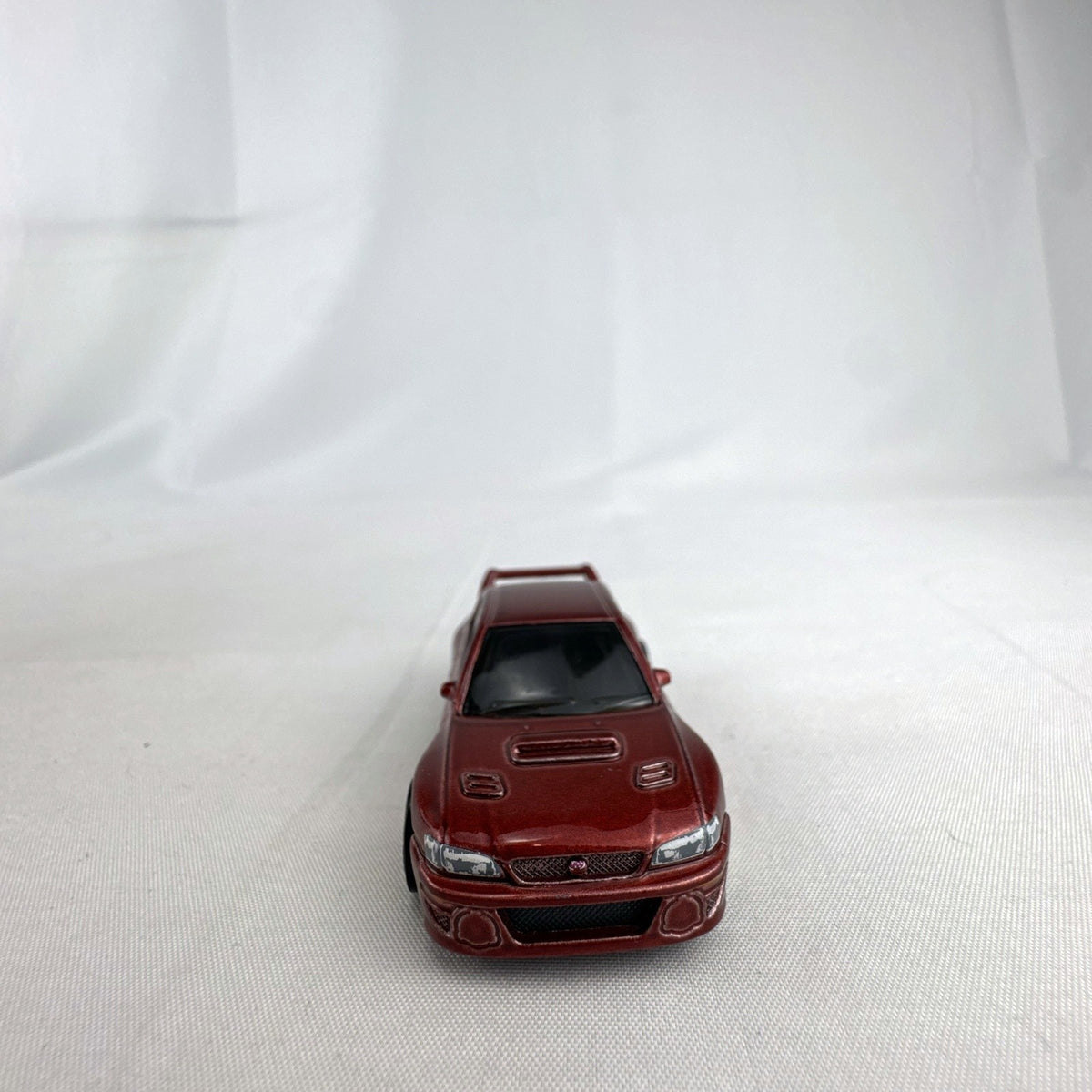 Hot Wheels 1:64 scale 1998 Subaru Impreza 22B STi-Version diecast car in dark metallic red with gold wheels