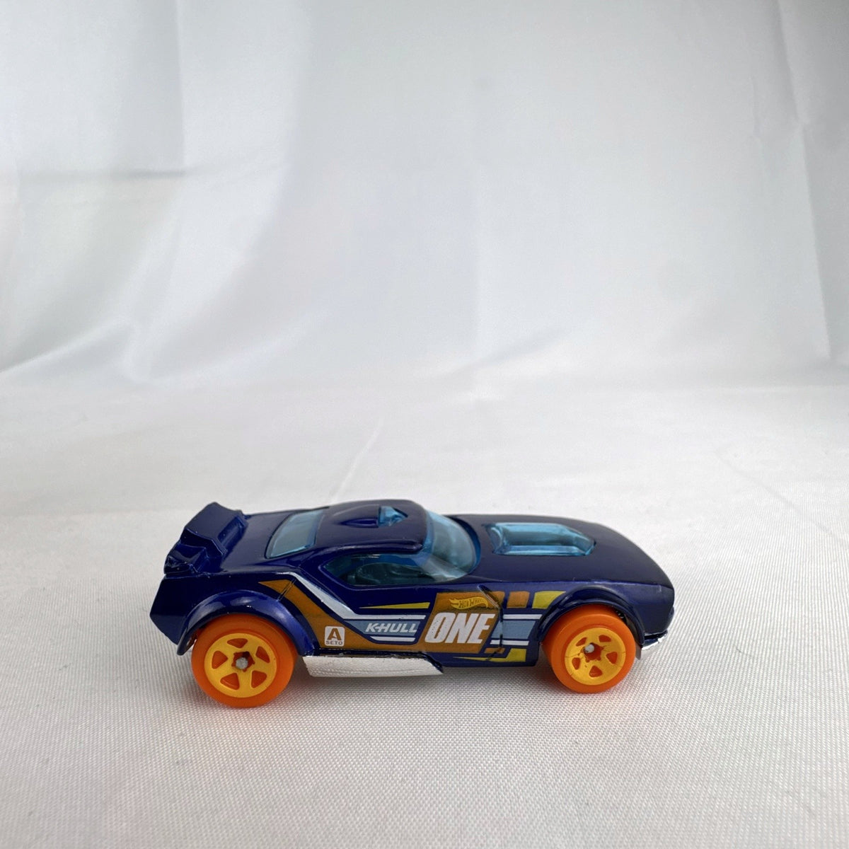 Hot Wheels Fast Fish 1:64 scale diecast car in dark blue with orange 5-spoke wheels and chrome base