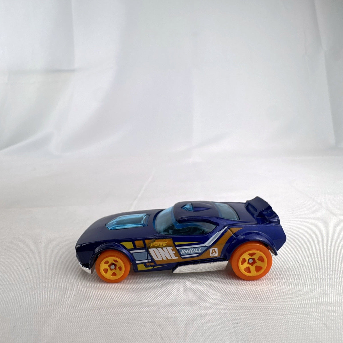 Hot Wheels Fast Fish 1:64 scale diecast car in dark blue with orange 5-spoke wheels and chrome base