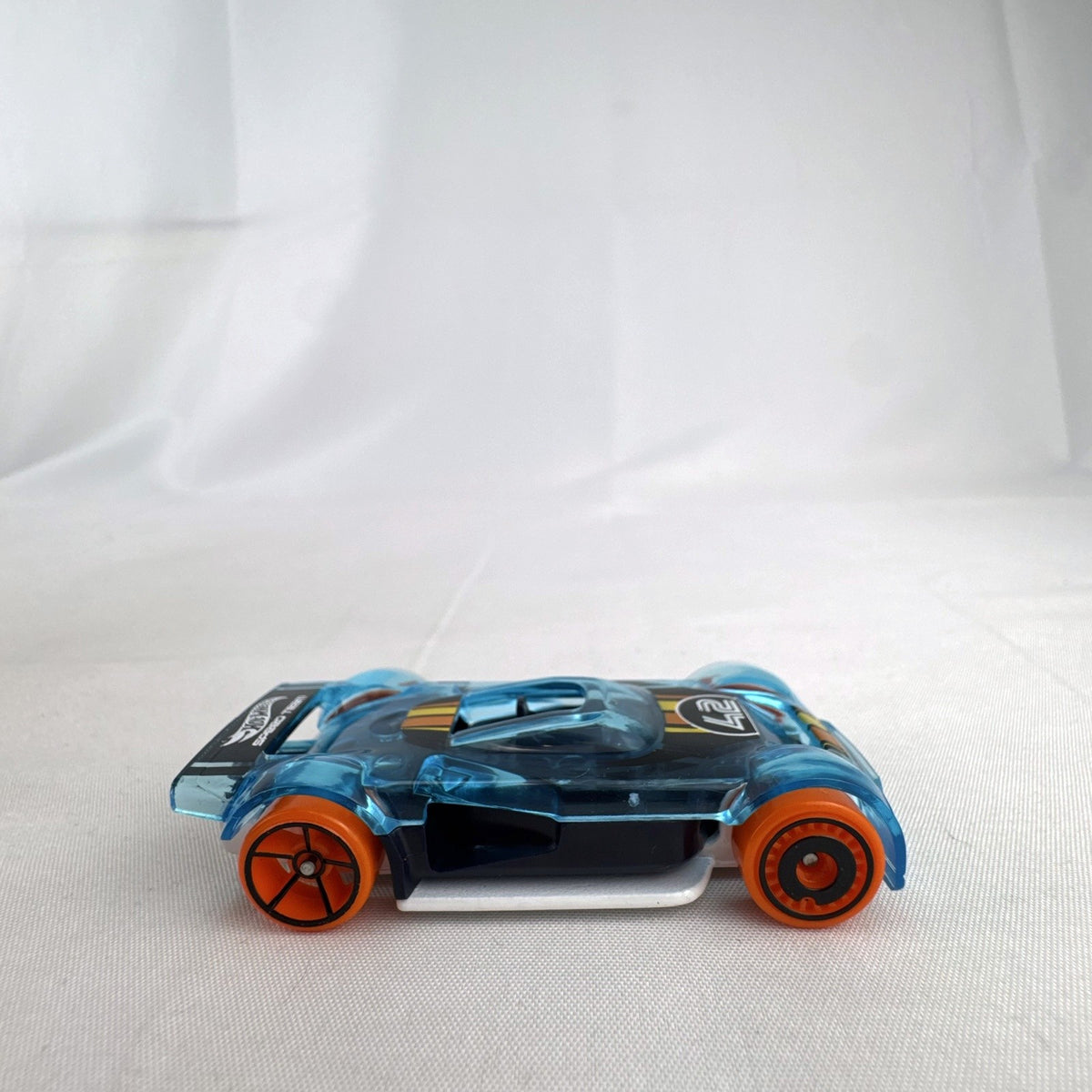 Hot Wheels Mach It Go 1:64 scale diecast race car in translucent blue with orange wheels and number 42 livery