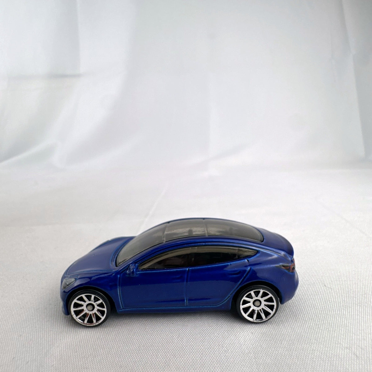 Hot Wheels 1:64 scale metallic blue Tesla Model 3 diecast car with smoke-tinted glass roof
