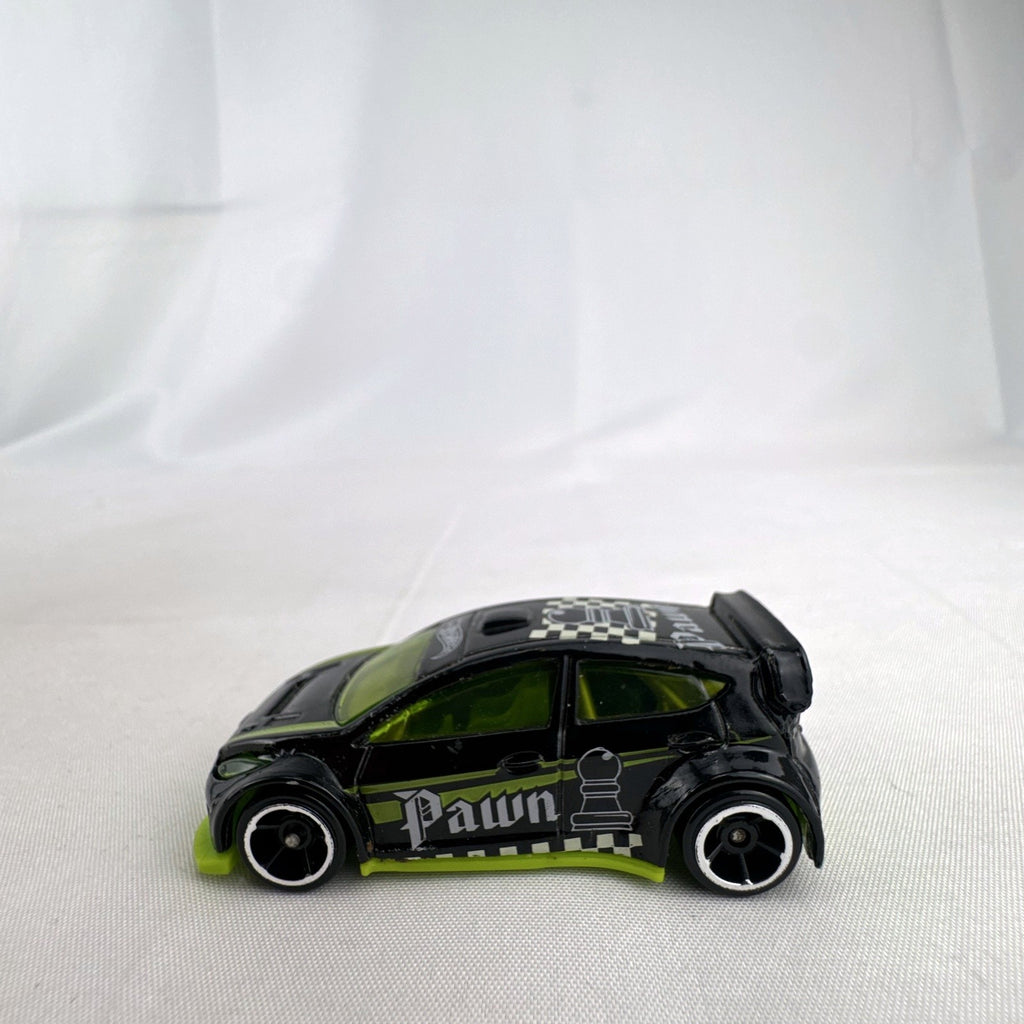 Hot Wheels 1:64 scale 2012 Ford Fiesta diecast car in black with green trim and HW Checkmate pawn graphics