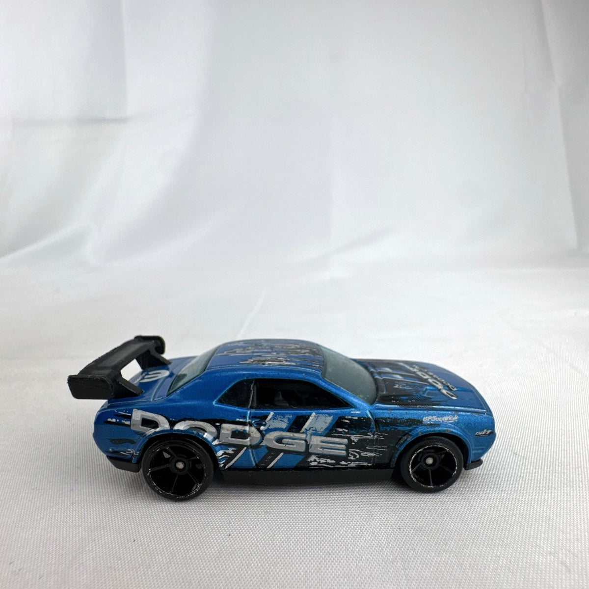 Hot Wheels 1:64 scale Dodge Challenger Drift Car in metallic blue with Mopar graphics and black rear spoiler