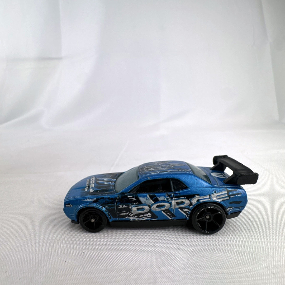 Hot Wheels 1:64 scale Dodge Challenger Drift Car in metallic blue with Mopar graphics and black rear spoiler