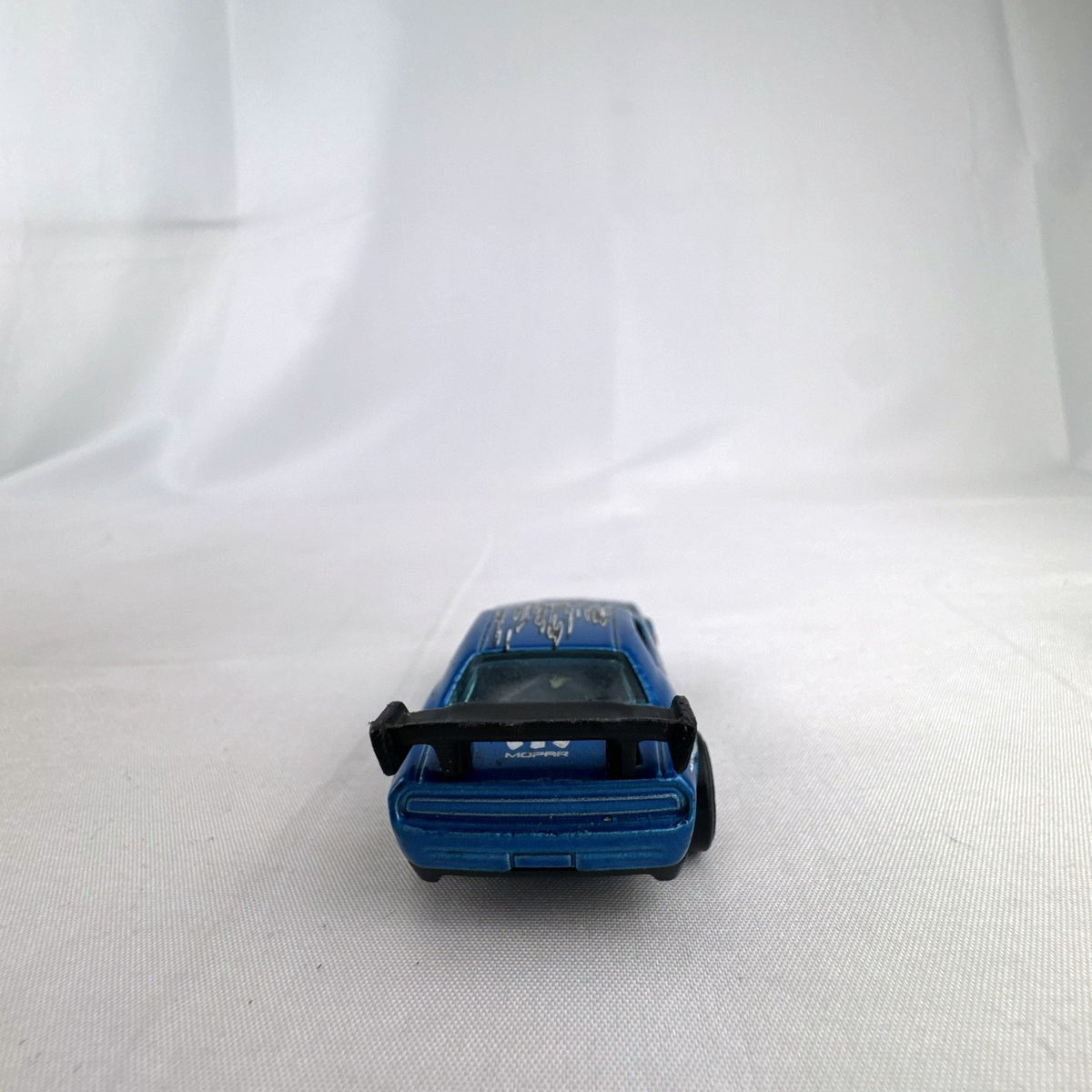 Hot Wheels 1:64 scale Dodge Challenger Drift Car in metallic blue with Mopar graphics and black rear spoiler