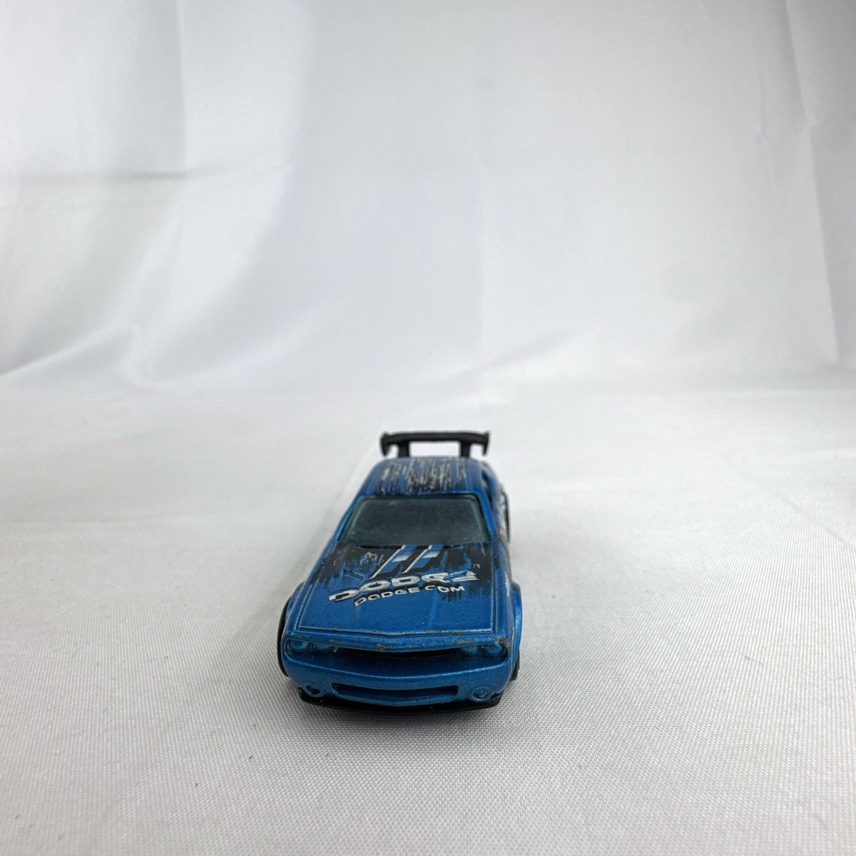 Hot Wheels 1:64 scale Dodge Challenger Drift Car in metallic blue with Mopar graphics and black rear spoiler
