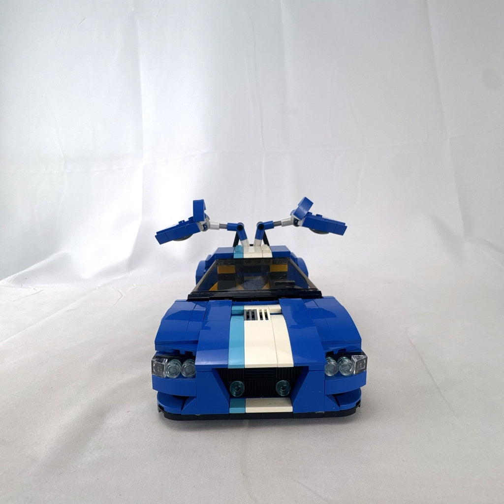 Assembled blue LEGO Creator 31070 Turbo Track Racer car with open gull-wing doors and instruction manual