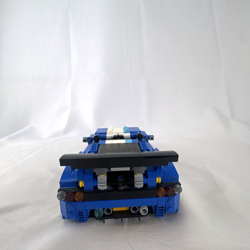 Assembled blue LEGO Creator 31070 Turbo Track Racer car with open gull-wing doors and instruction manual