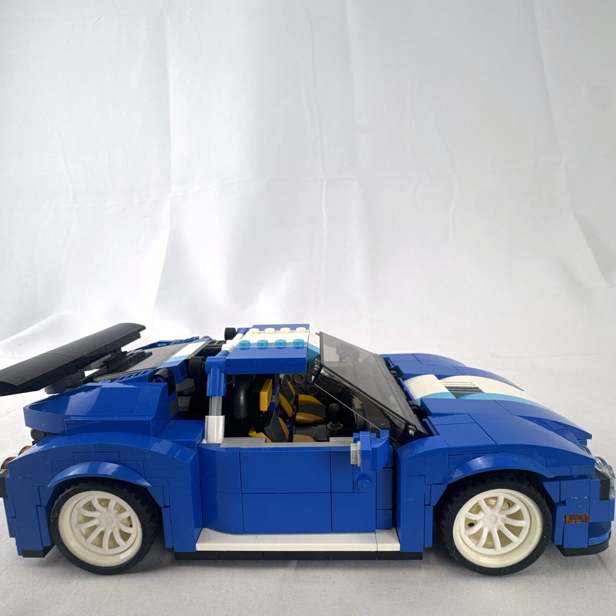 Assembled blue LEGO Creator 31070 Turbo Track Racer car with open gull-wing doors and instruction manual
