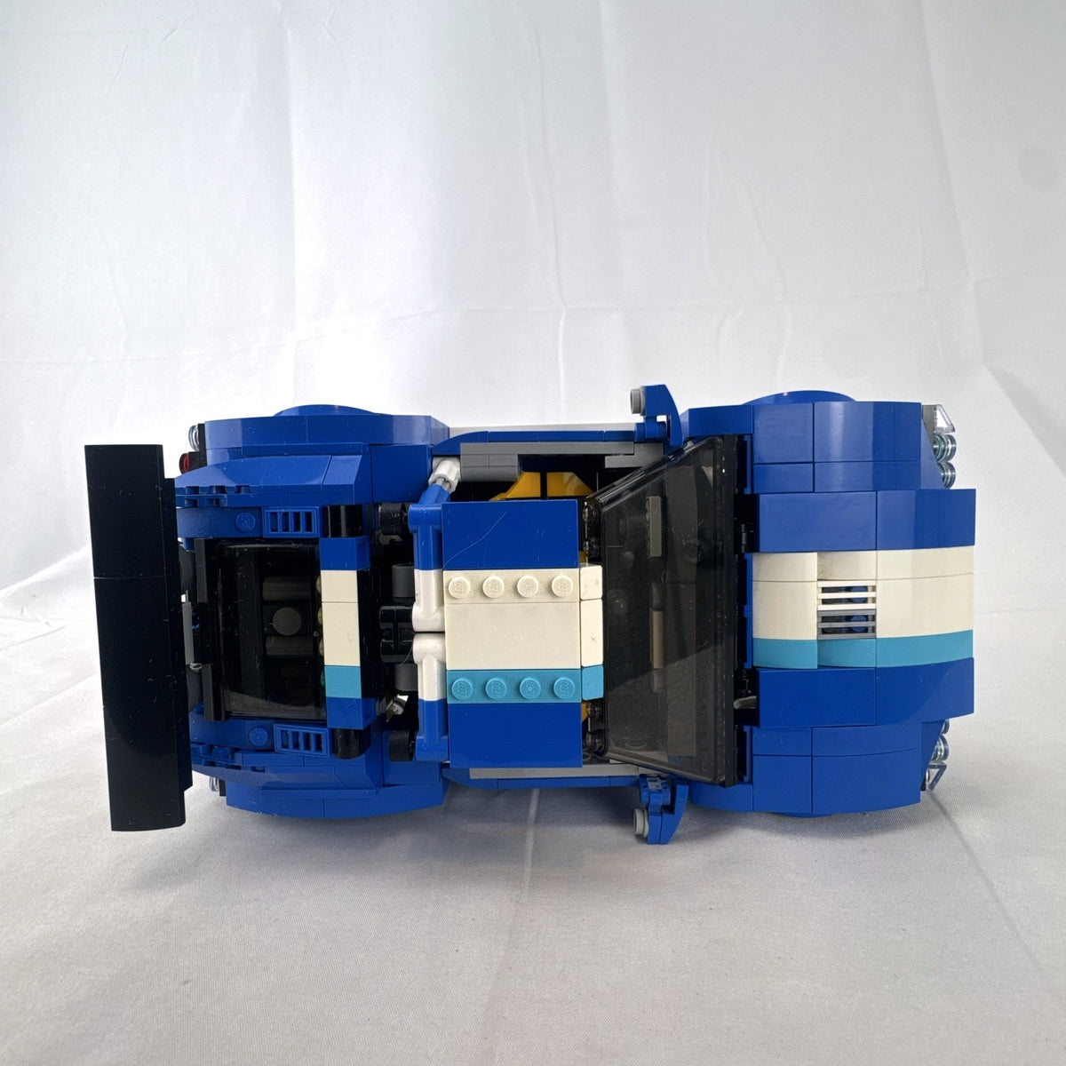 Assembled blue LEGO Creator 31070 Turbo Track Racer car with open gull-wing doors and instruction manual
