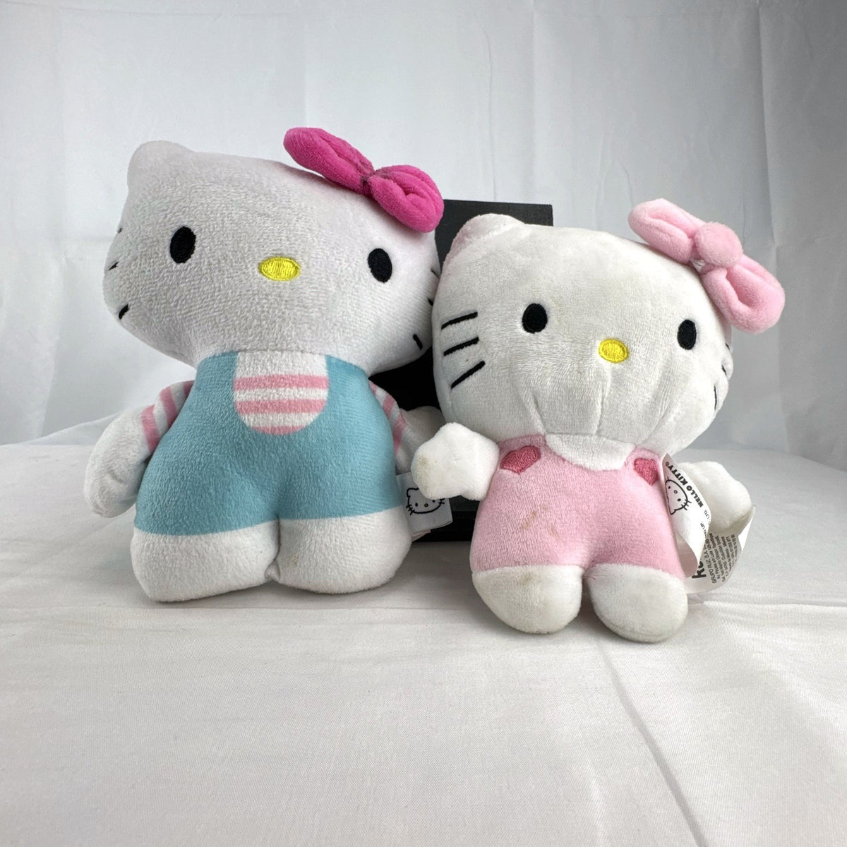 Pair of Sanrio Hello Kitty plush dolls wearing blue and pink overalls, measuring approximately 7 inches tall.