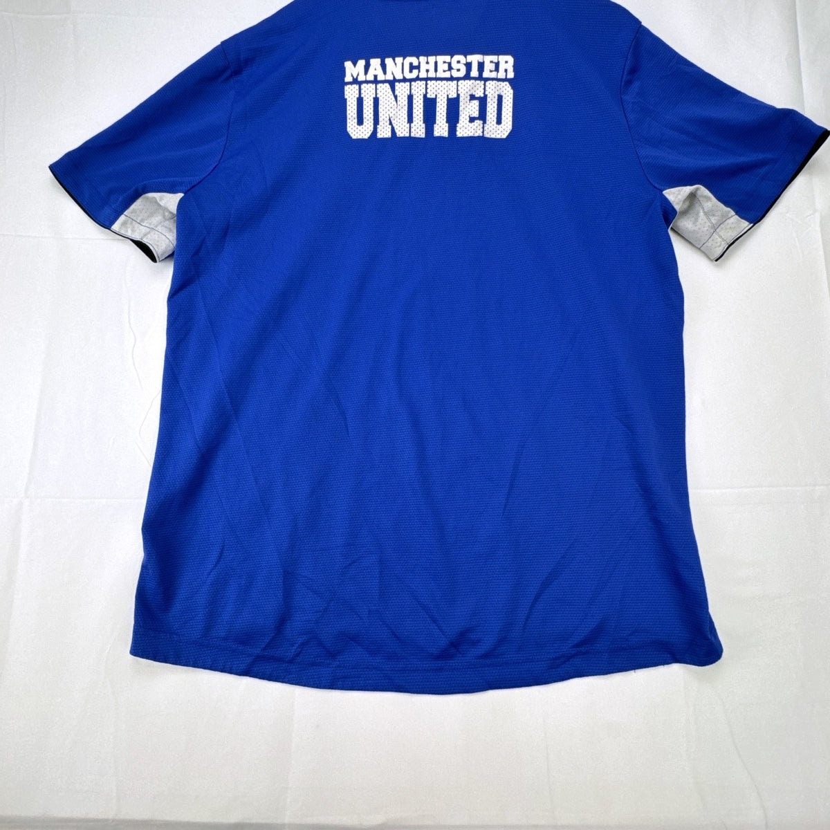 Manchester United men's large royal blue soccer jersey with embroidered chest crest and striped ribbed collar.
