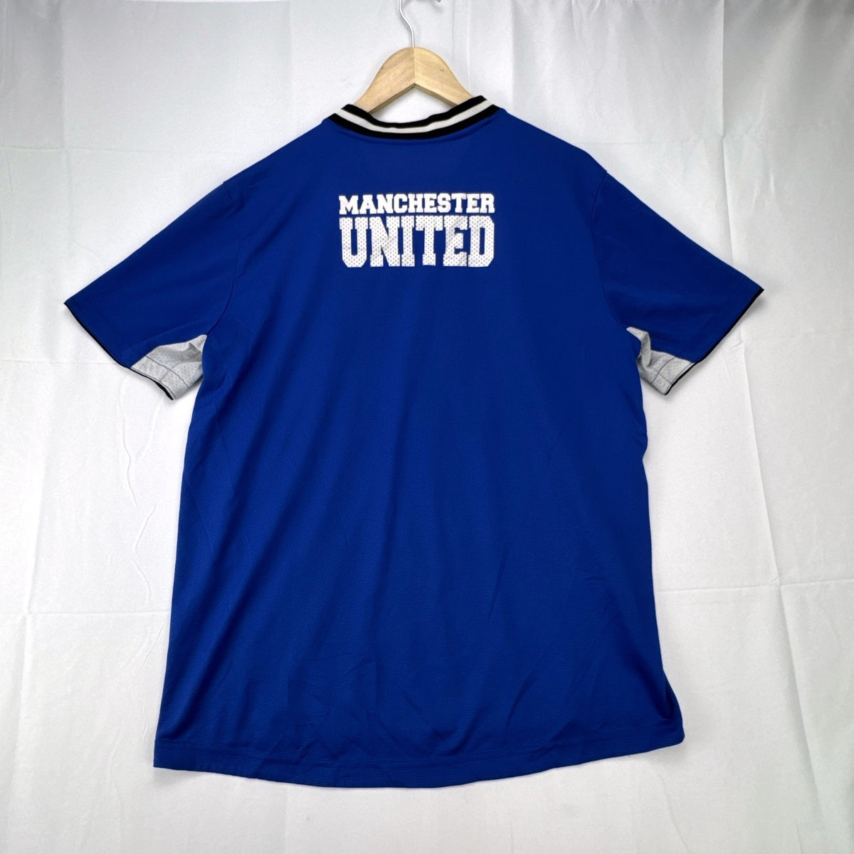 Manchester United men's large royal blue soccer jersey with embroidered chest crest and striped ribbed collar.