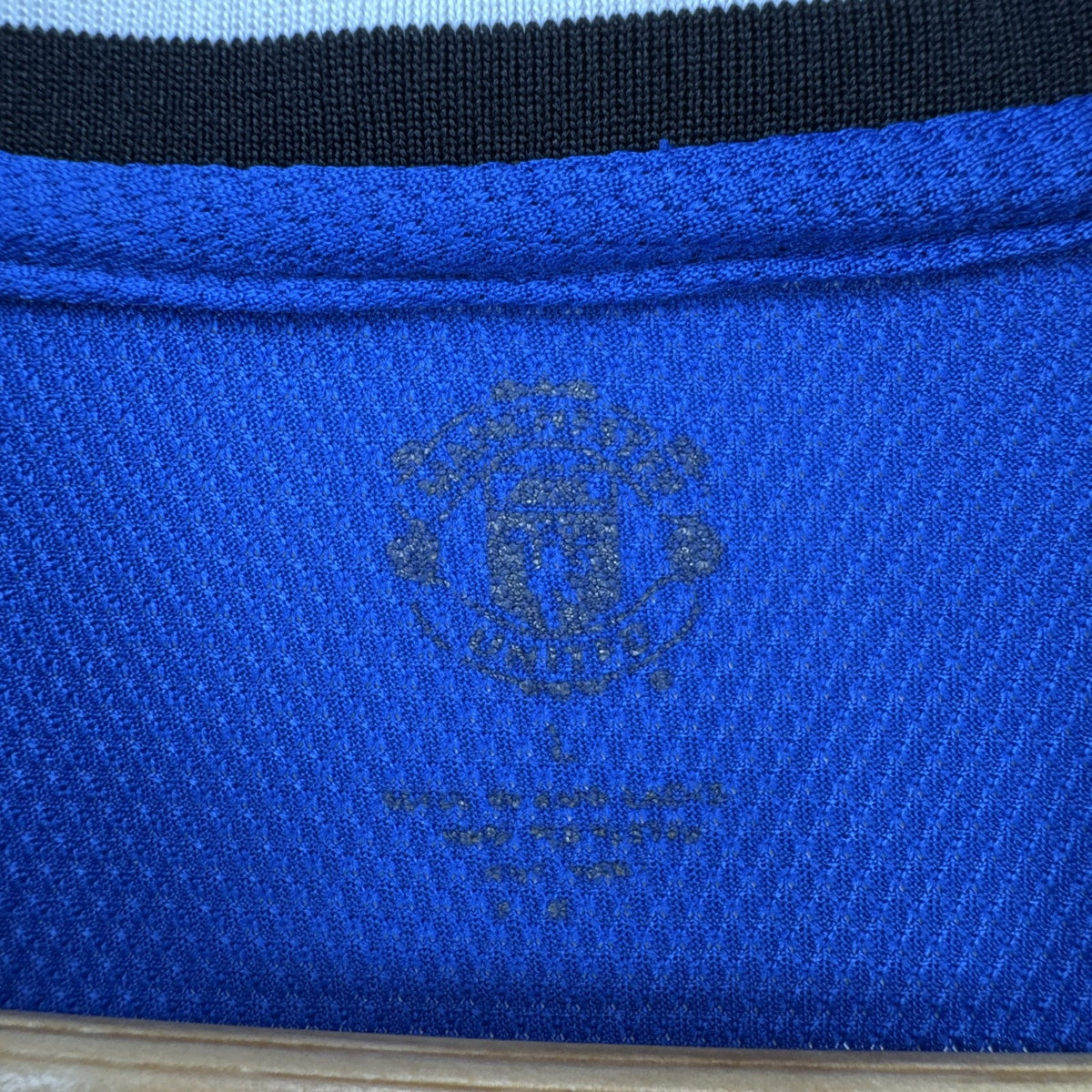 Manchester United men's large royal blue soccer jersey with embroidered chest crest and striped ribbed collar.