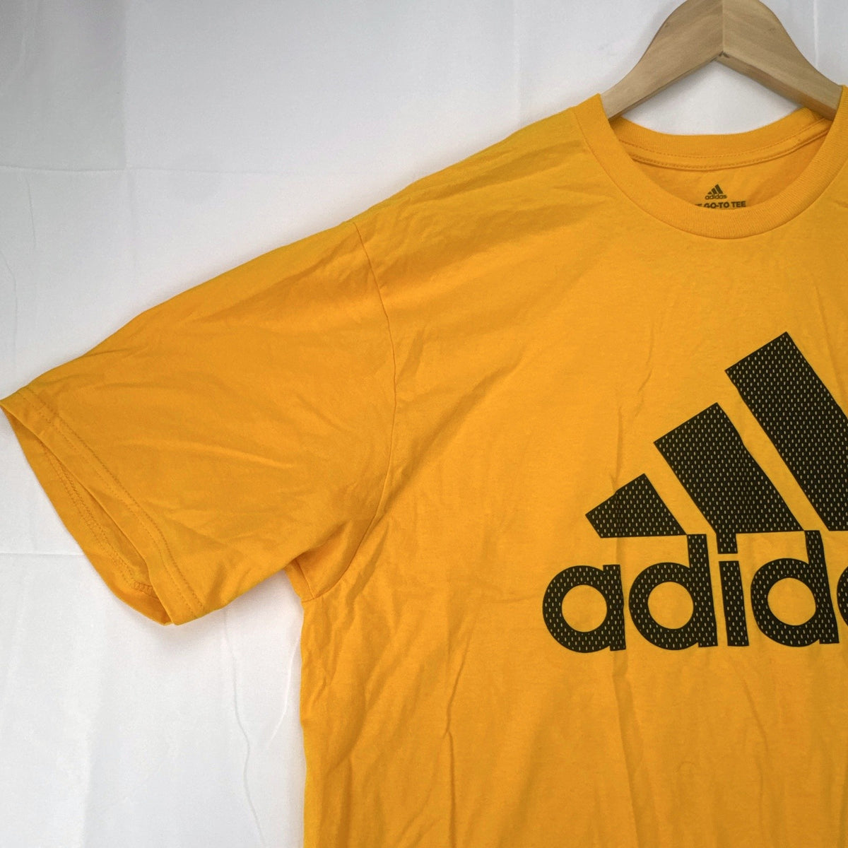 Front view of yellow adidas The Go-To graphic t-shirt in men's XL with black Badge of Sport logo