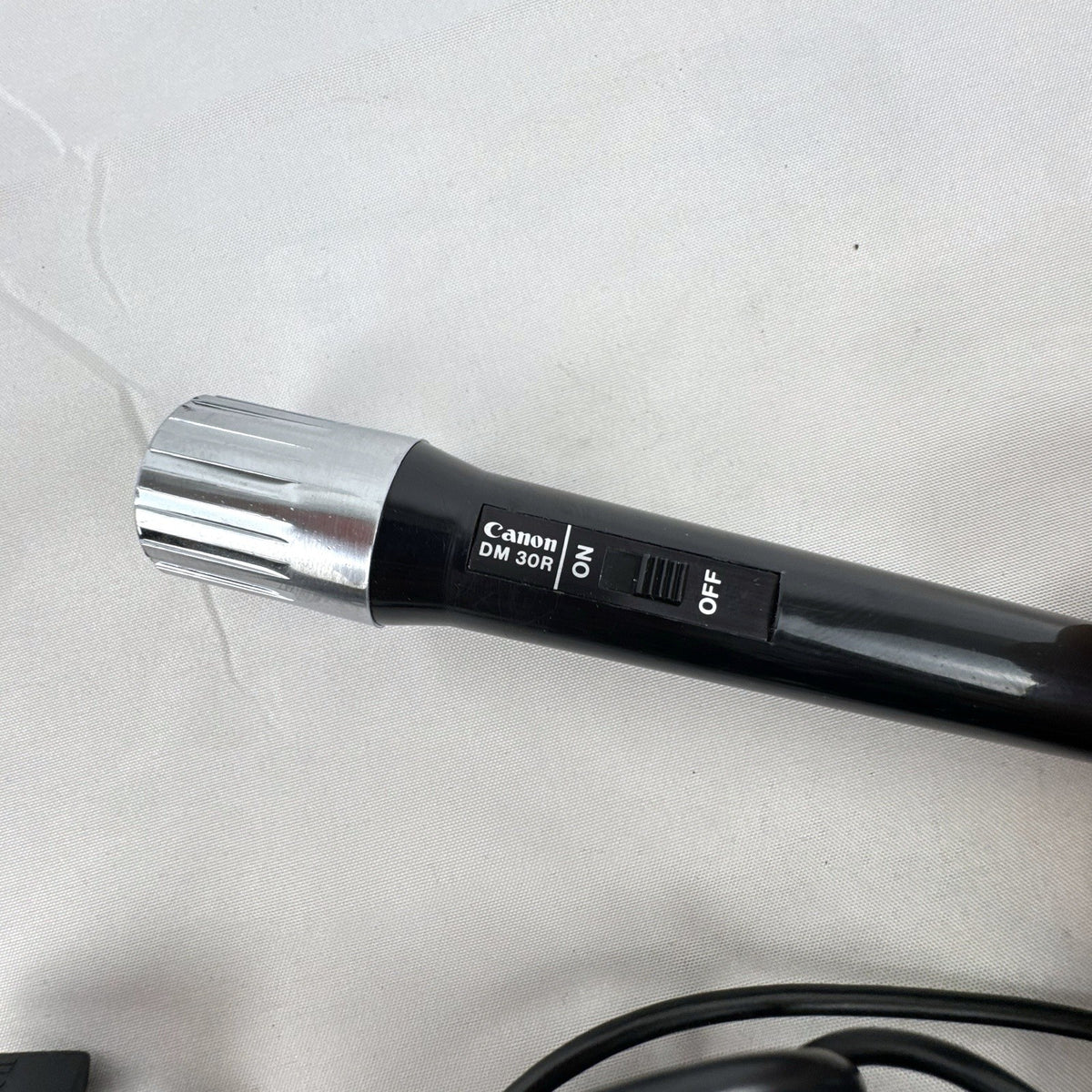 Black Canon DM 30R dynamic handheld microphone with chrome grille and attached 3.5mm cable