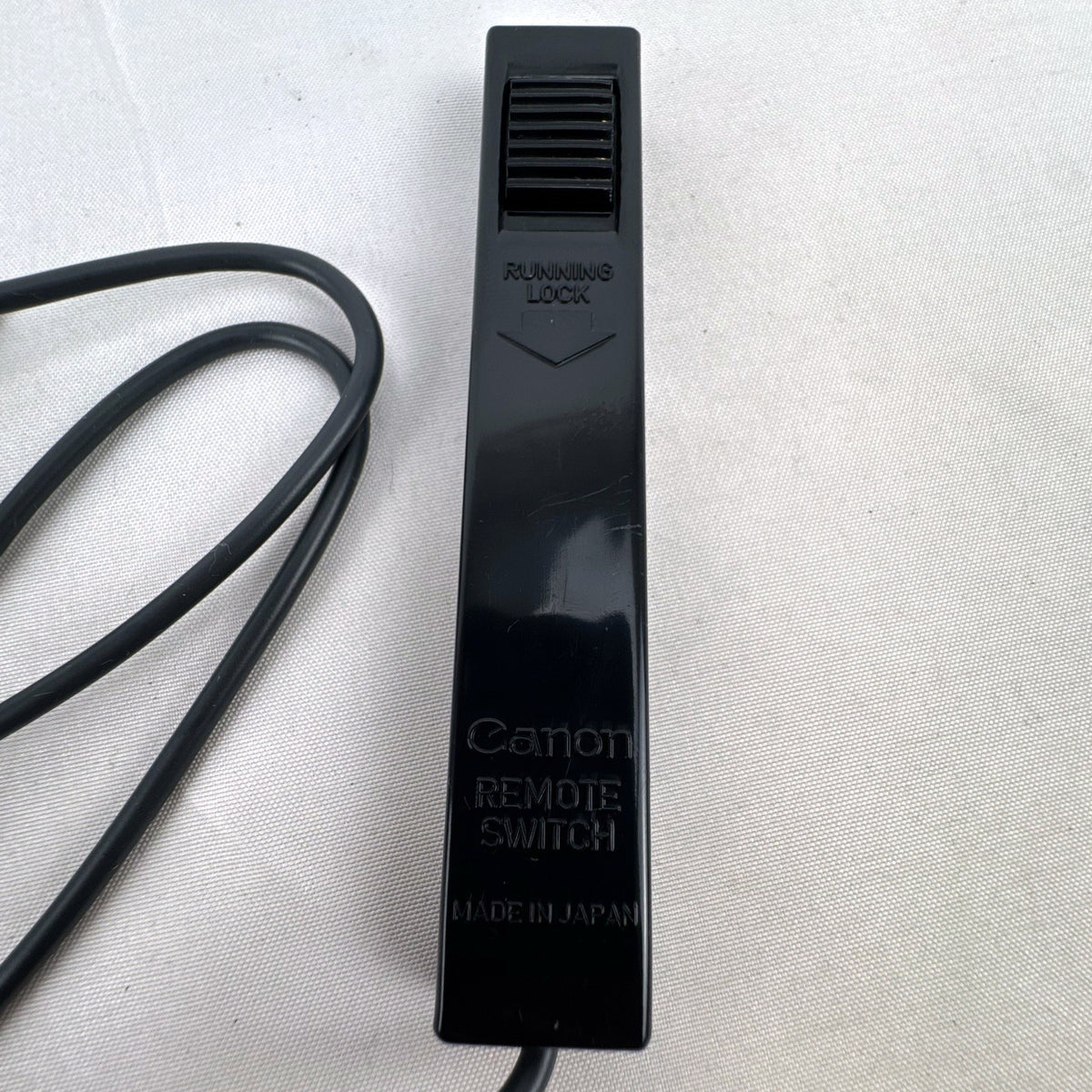 Black vintage Canon wired shutter release remote switch with 2.5mm connector plug and running lock.