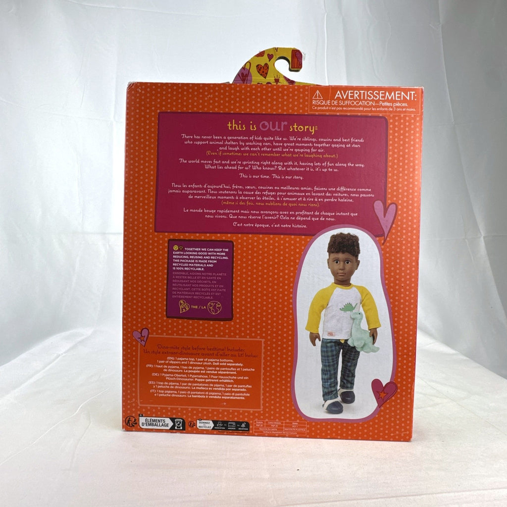 Our Generation Dino-Snores pajama outfit for 18-inch dolls in packaging with plaid pants and dinosaur plush.
