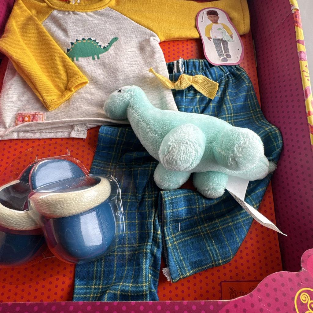 Our Generation Dino-Snores pajama outfit for 18-inch dolls in packaging with plaid pants and dinosaur plush.
