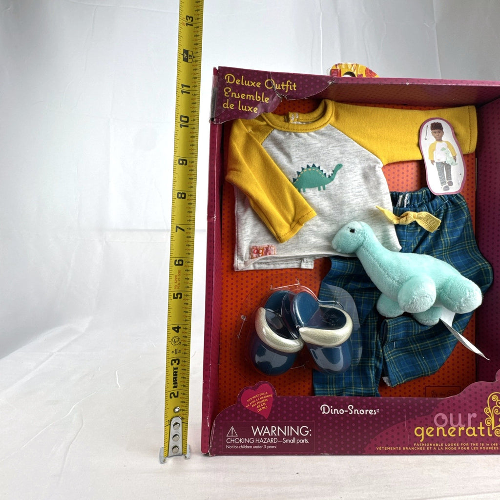 Our Generation Dino-Snores pajama outfit for 18-inch dolls in packaging with plaid pants and dinosaur plush.
