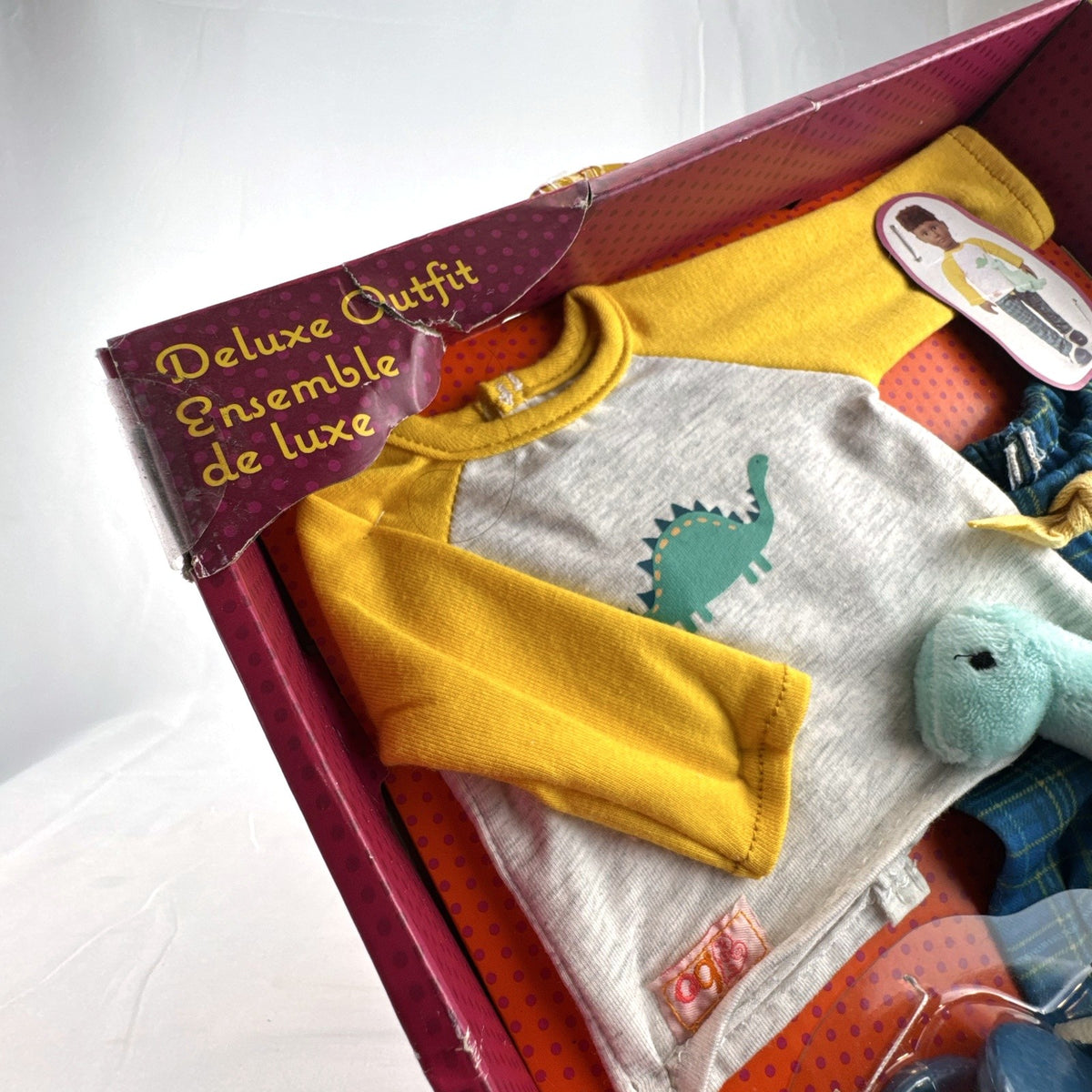 Our Generation Dino-Snores pajama outfit for 18-inch dolls in packaging with plaid pants and dinosaur plush.