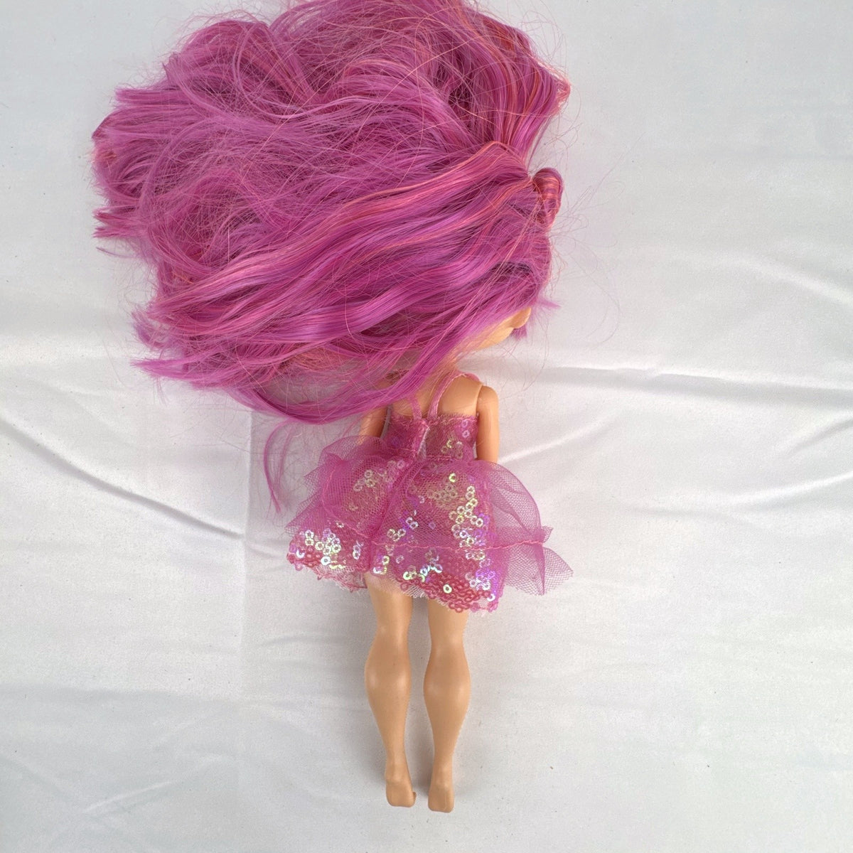 MGA Entertainment L.O.L. Surprise O.M.G. Lights Dazzle 10-inch fashion doll with pink hair in a sparkly sequin dress.