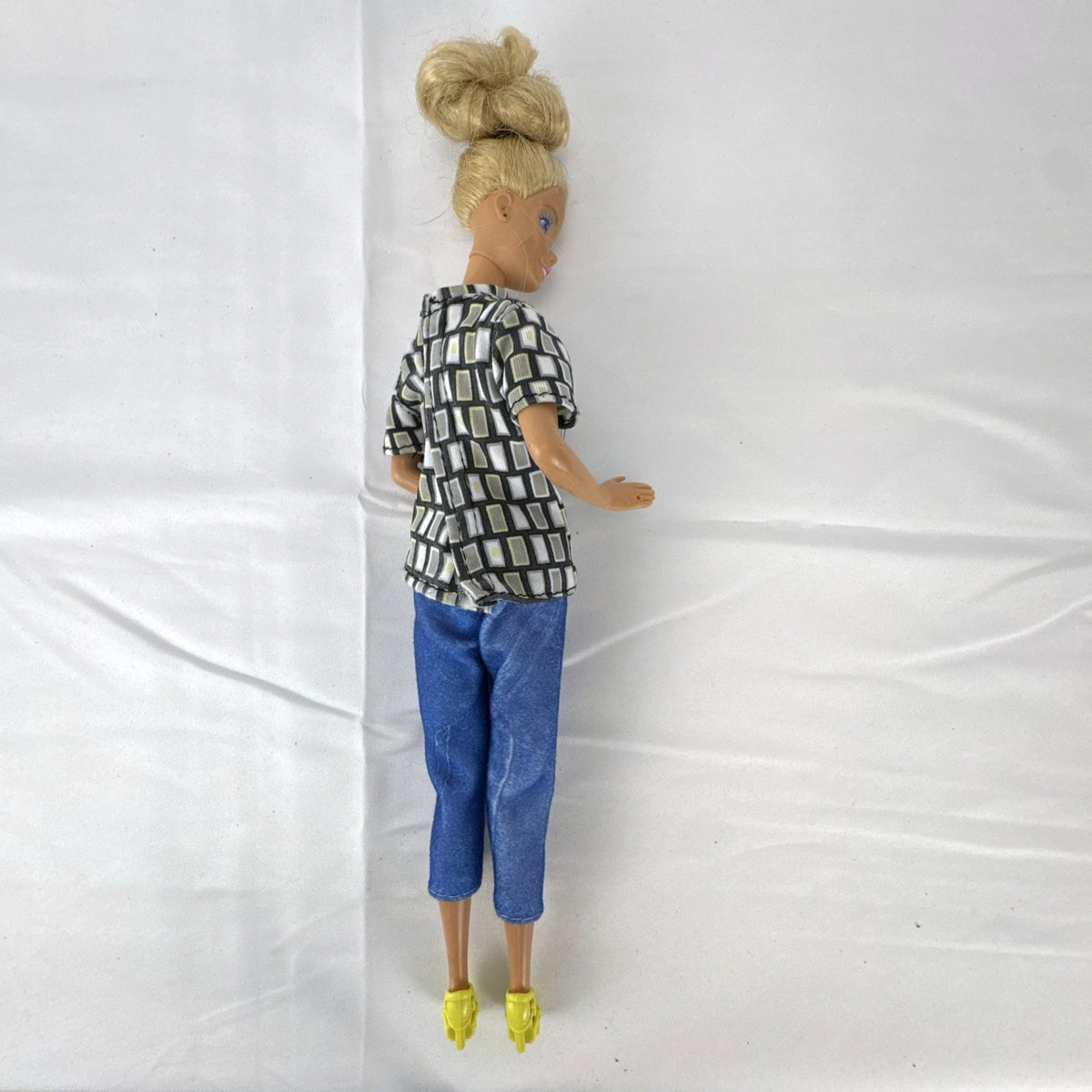 Vintage Mattel Barbie 12-inch doll with blonde hair bun updo, geometric top, blue cropped pants, and yellow platform heels.