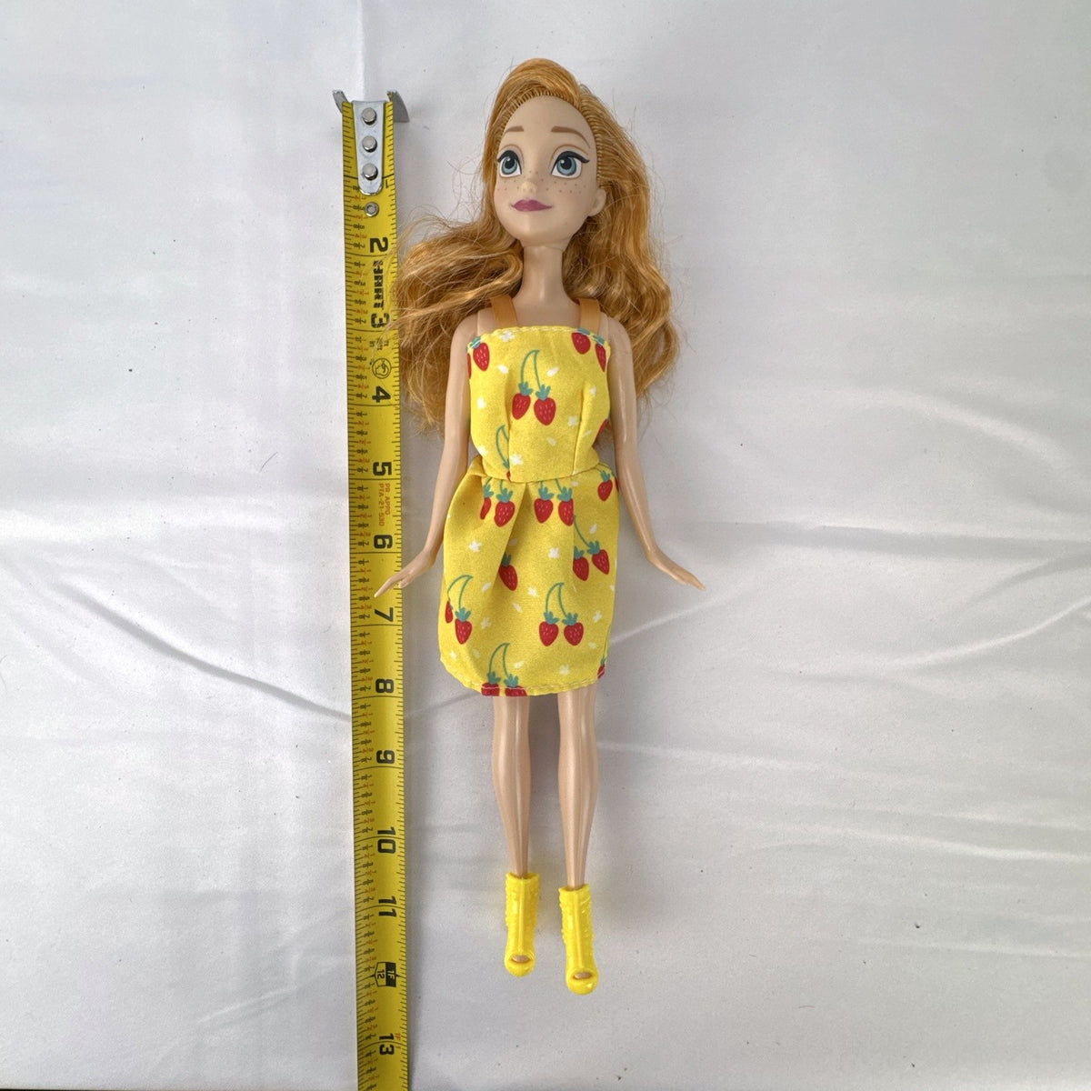 Mattel Disney Frozen Princess Anna 11-inch fashion doll wearing yellow strawberry dress and ankle booties