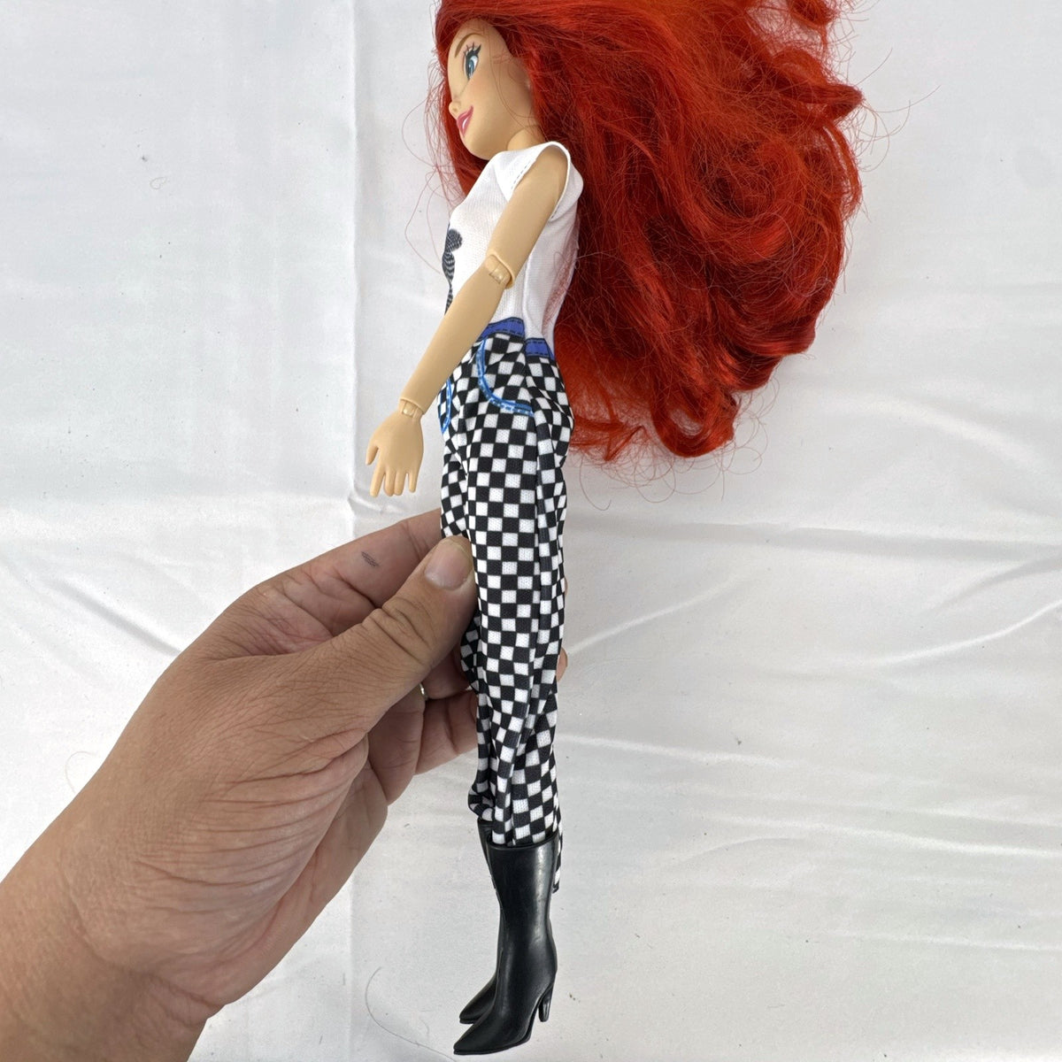 Articulated 11-inch Disney Ariel fashion doll with red hair in casual checkered pants and graphic t-shirt
