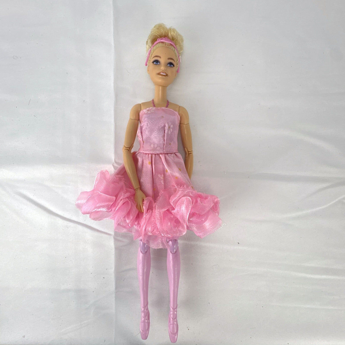 Mattel Barbie 12-inch articulated ballerina doll wearing a pink ruffled tutu dress with blonde bun hair.