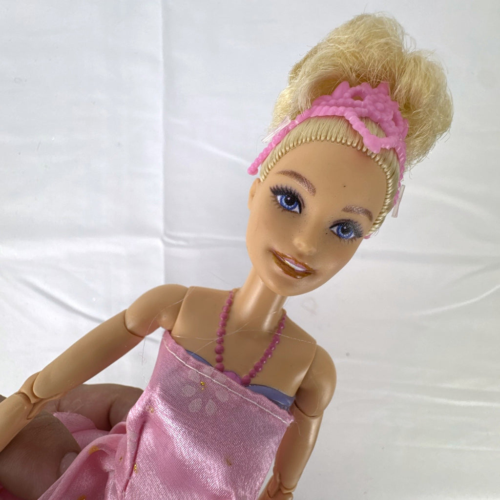 Mattel Barbie 12-inch articulated ballerina doll wearing a pink ruffled tutu dress with blonde bun hair.