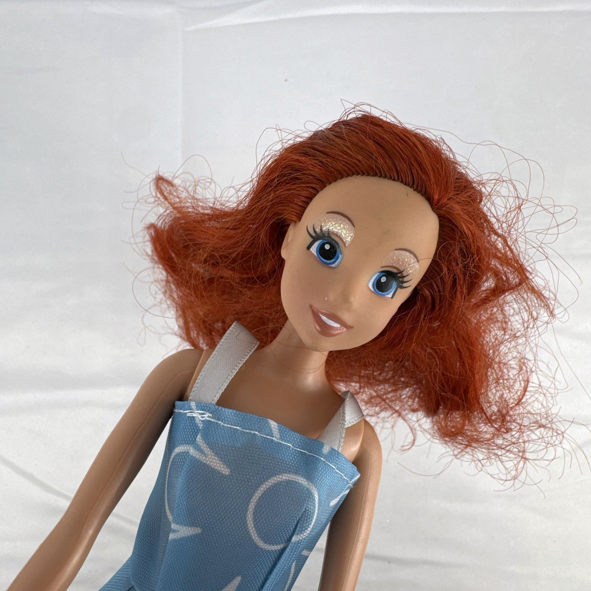 Disney Princess Ariel 11-inch fashion doll with red hair in a blue floral dress and white sneakers