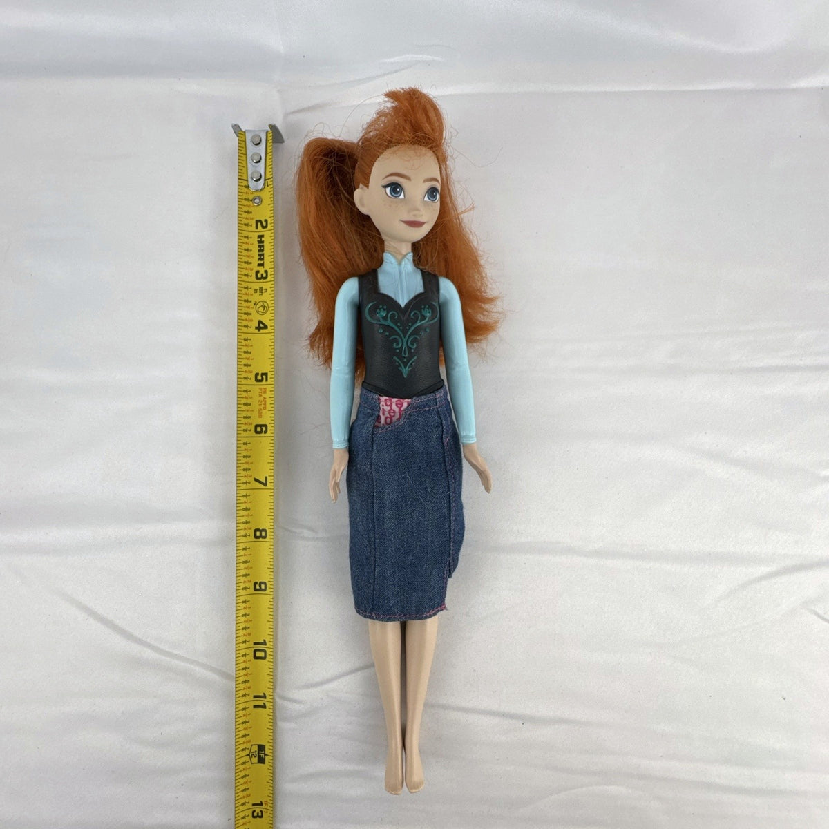 Mattel Disney Frozen 11-inch Princess Anna doll with red hair, molded bodice, and denim skirt.