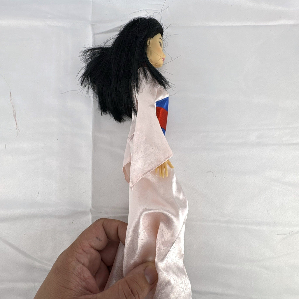 Vintage 12-inch Disney Mulan fashion doll wearing a pink satin matchmaker gown with red and blue sash