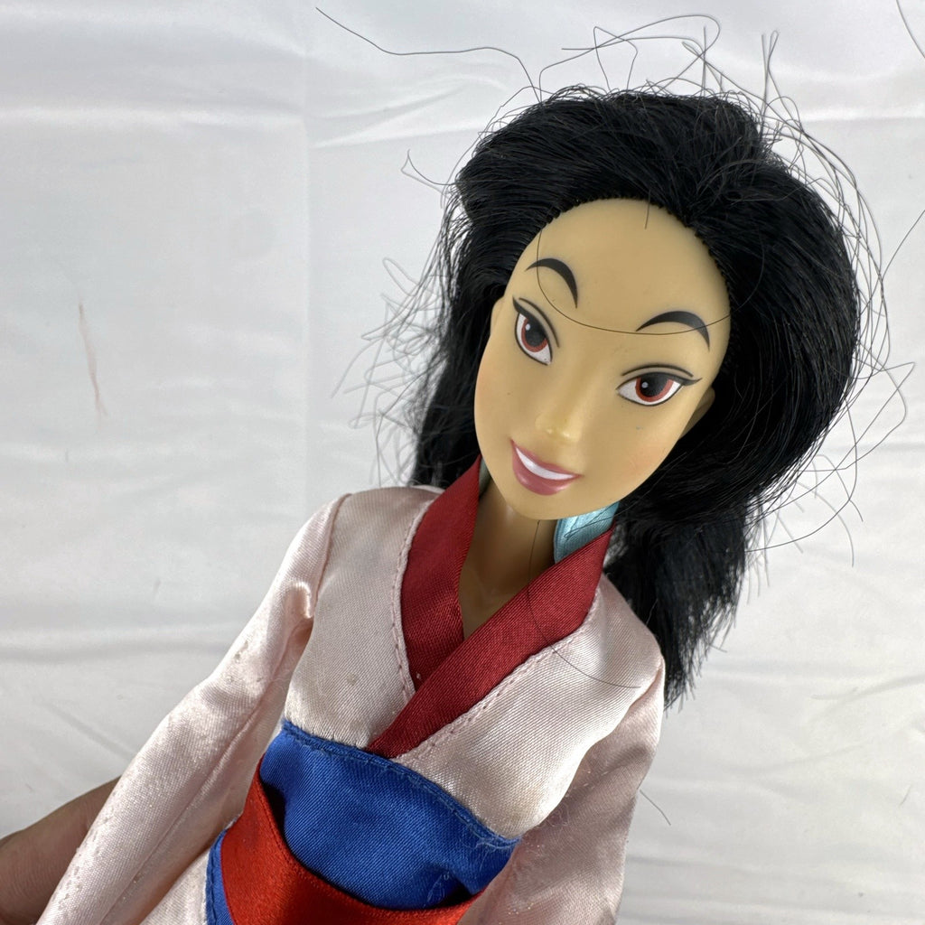 Vintage 12-inch Disney Mulan fashion doll wearing a pink satin matchmaker gown with red and blue sash