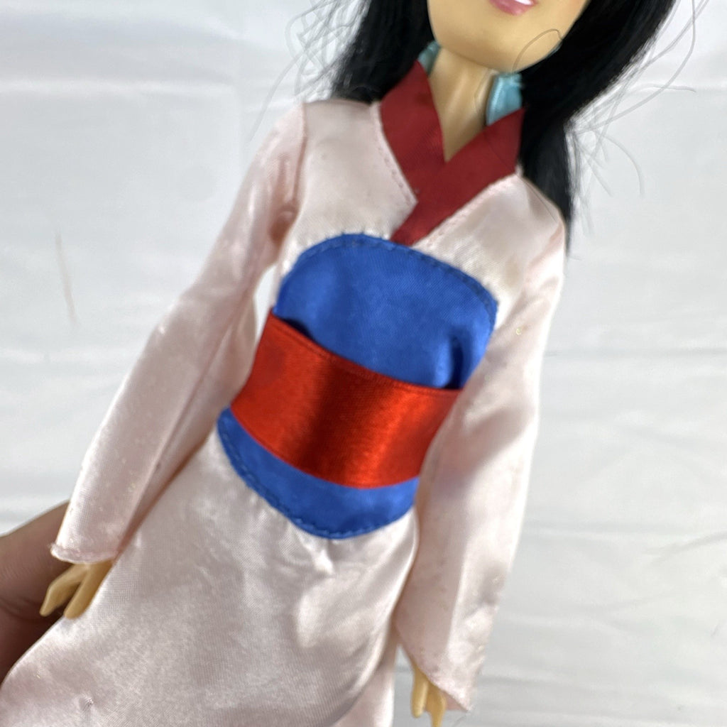 Vintage 12-inch Disney Mulan fashion doll wearing a pink satin matchmaker gown with red and blue sash