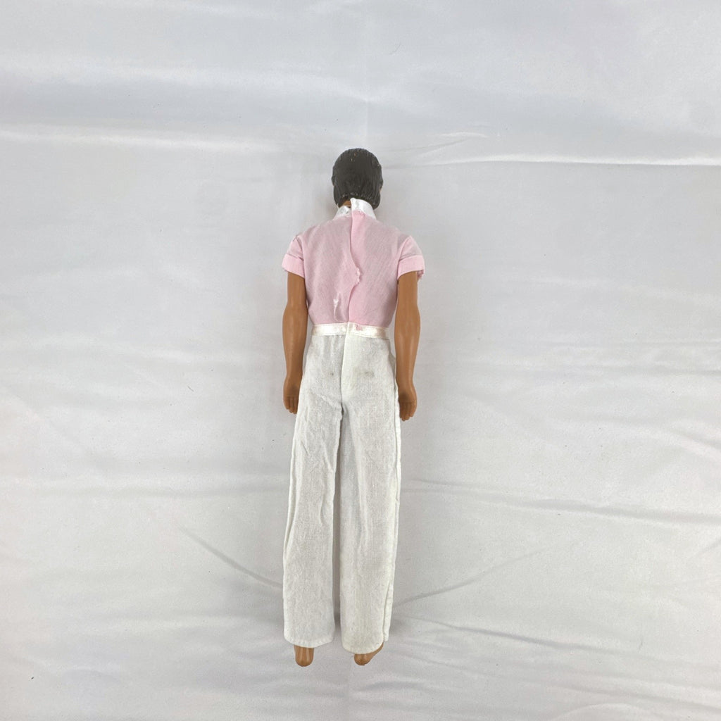 Mattel Barbie Ken 12-inch fashion doll with molded brown hair wearing a pink shirt with suspenders and white pants.