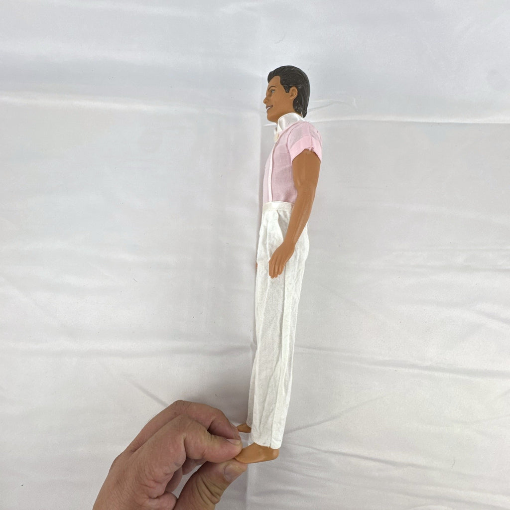 Mattel Barbie Ken 12-inch fashion doll with molded brown hair wearing a pink shirt with suspenders and white pants.