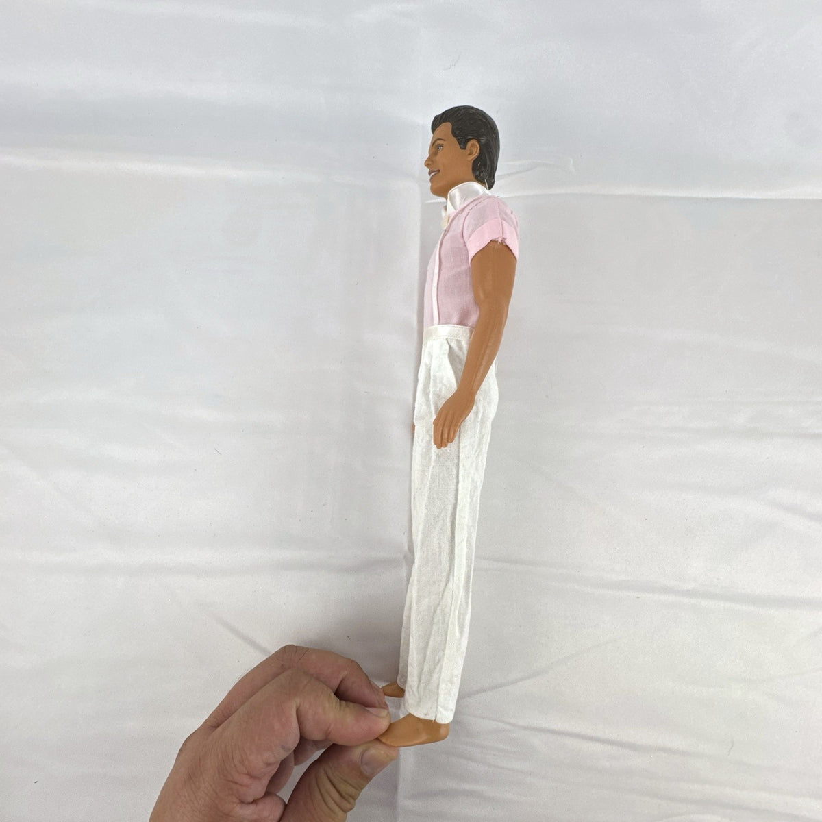 Mattel Barbie Ken 12-inch fashion doll with molded brown hair wearing a pink shirt with suspenders and white pants.
