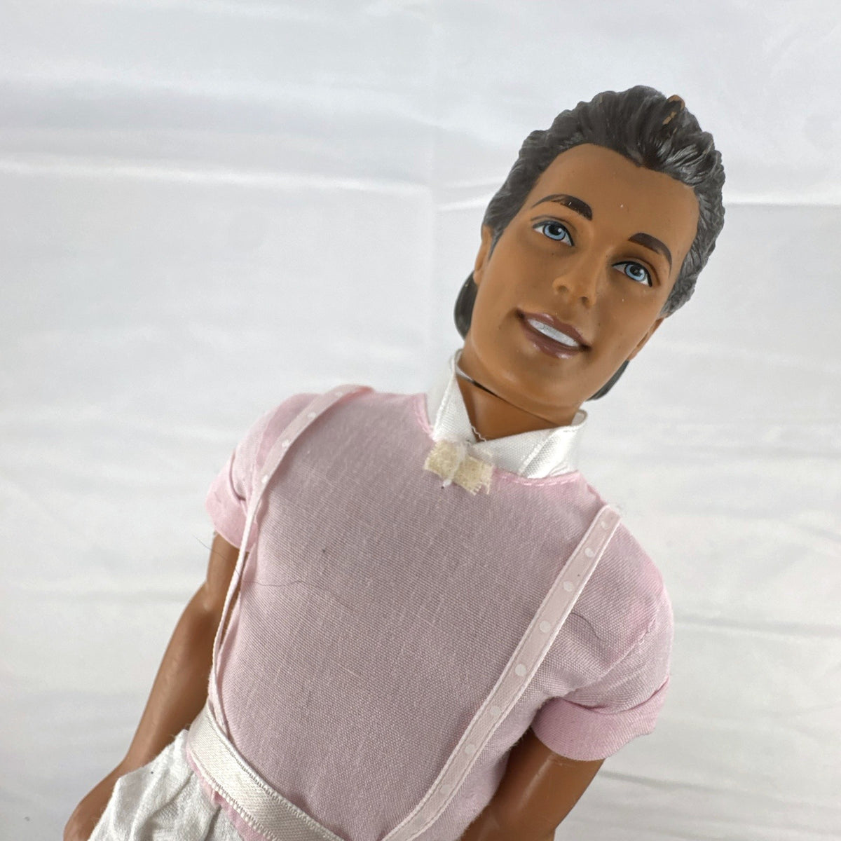 Mattel Barbie Ken 12-inch fashion doll with molded brown hair wearing a pink shirt with suspenders and white pants.