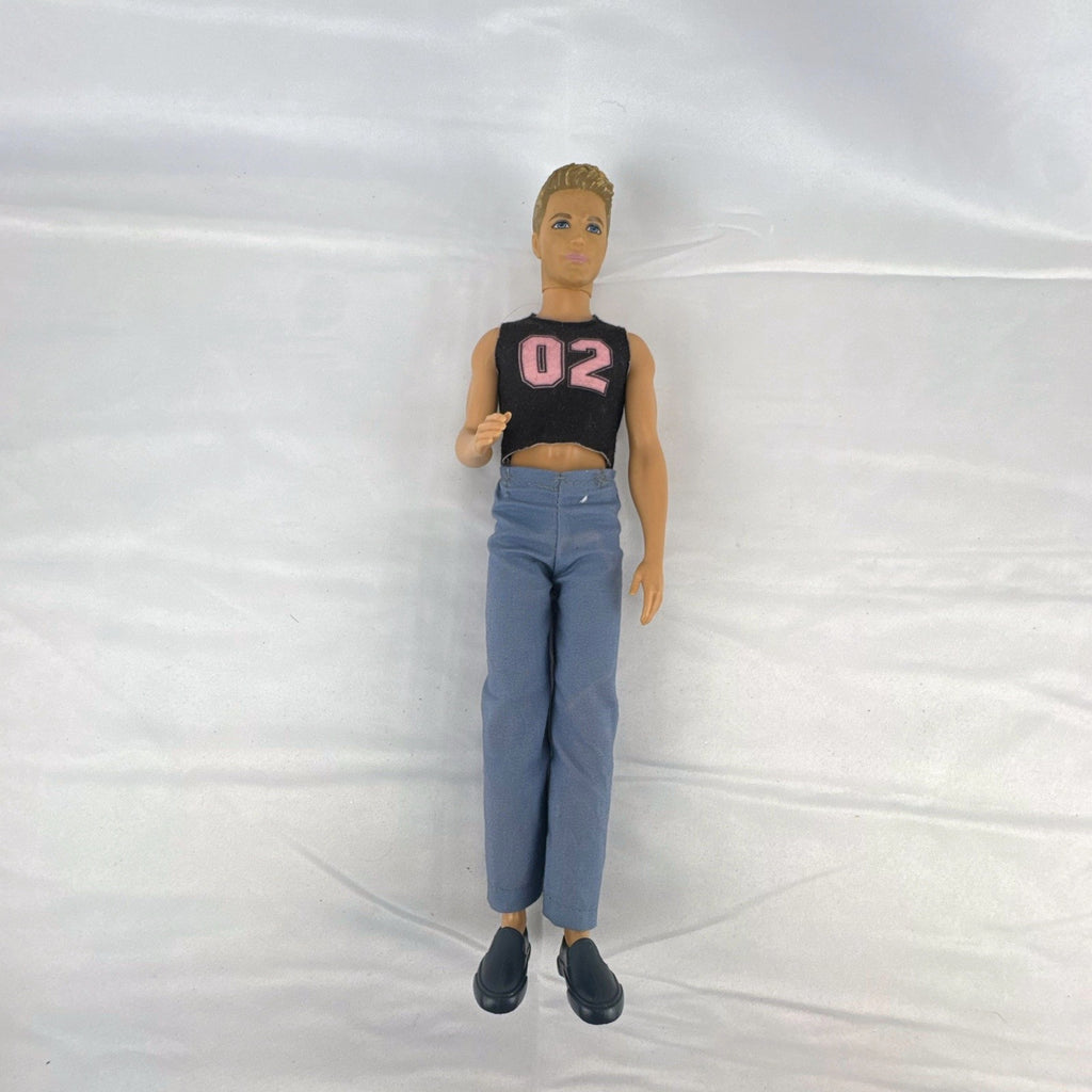 Mattel 12-inch Ken fashion doll with molded blonde hair, blue eyes, graphic sleeveless shirt, and blue trousers