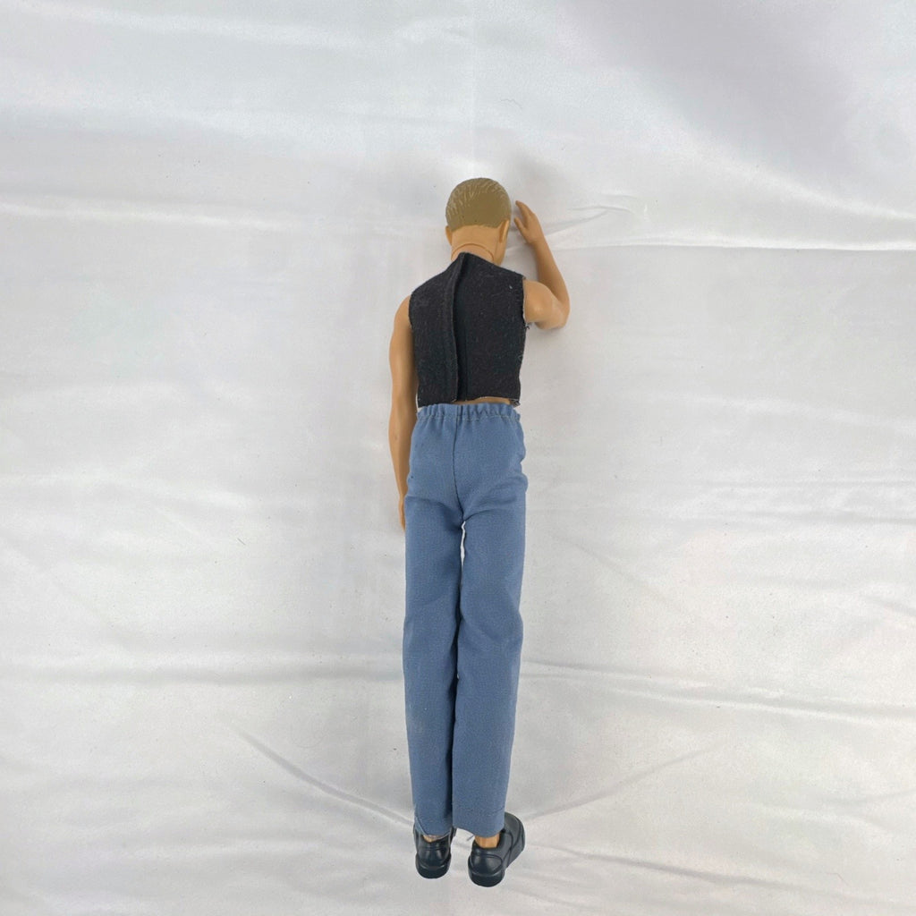 Mattel 12-inch Ken fashion doll with molded blonde hair, blue eyes, graphic sleeveless shirt, and blue trousers